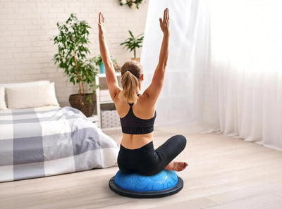 Woman exercising on a half balance ball in a bedroom
