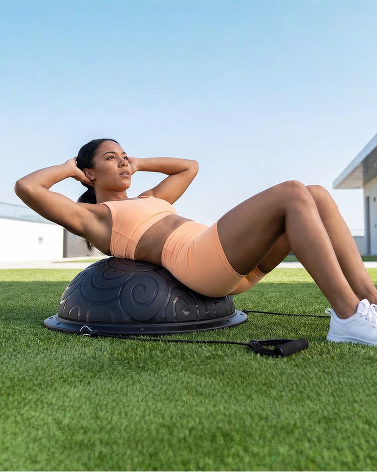 Woman exercising on a half balance ball outdoors