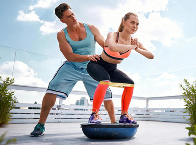 Two people using a balance trainer outdoors with a clear sky background