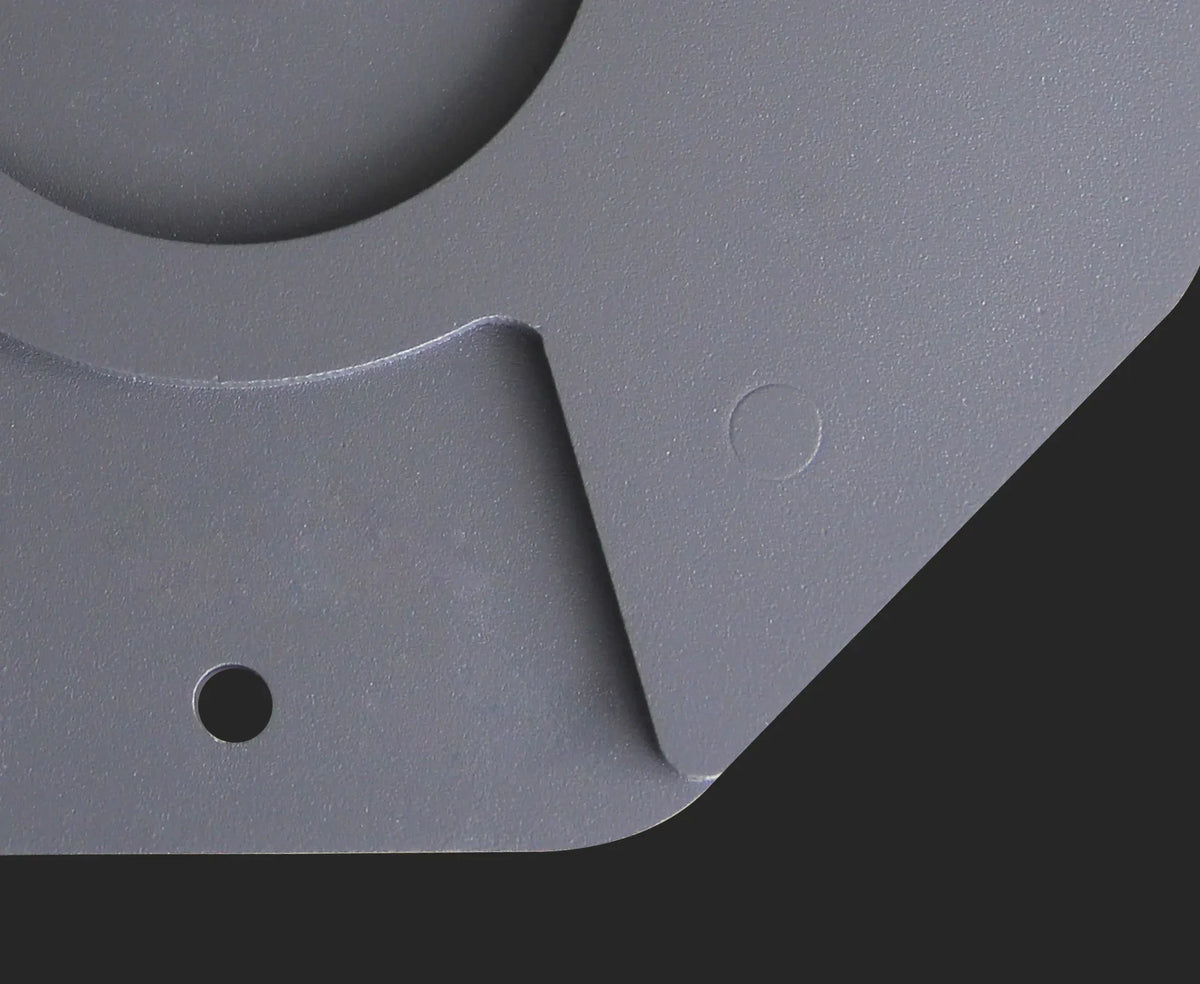 Close-up of a gray metal bracket with circular cutout and screw holes.